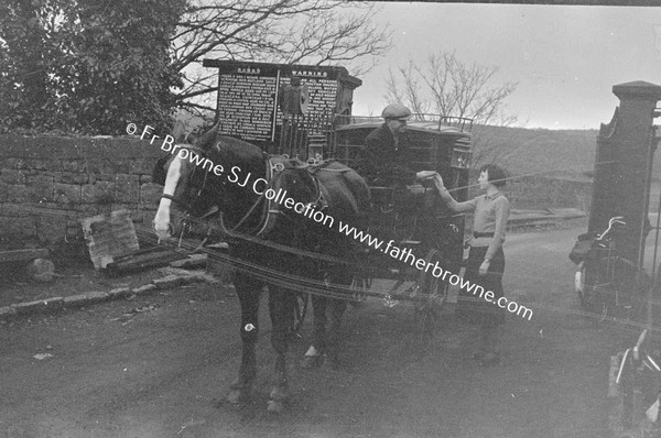 MAN WITH CARRIAGE PAYING TOLL TO YOUNG WOMAN